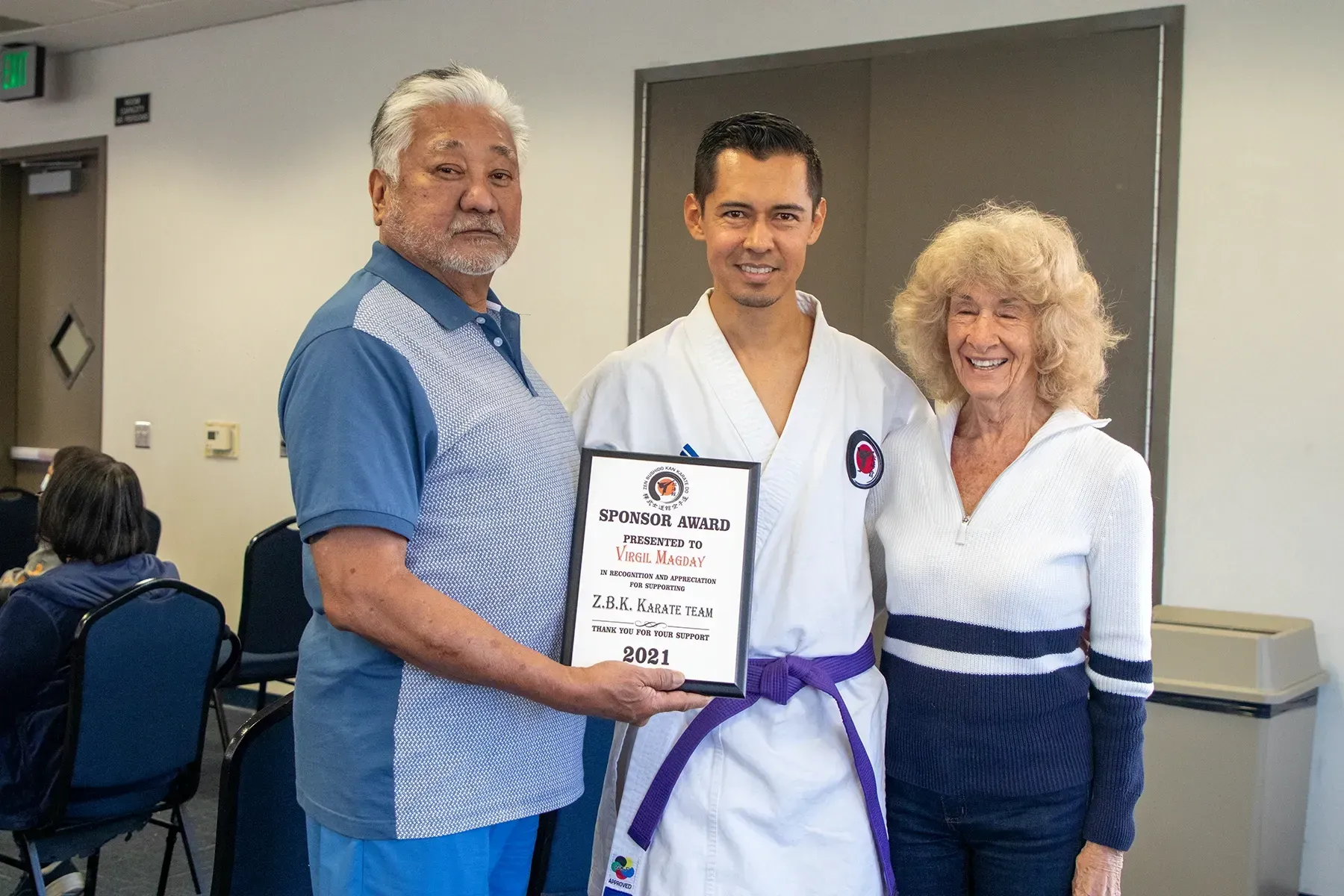 A man with a purple belt is being presented with a certificate by two men.