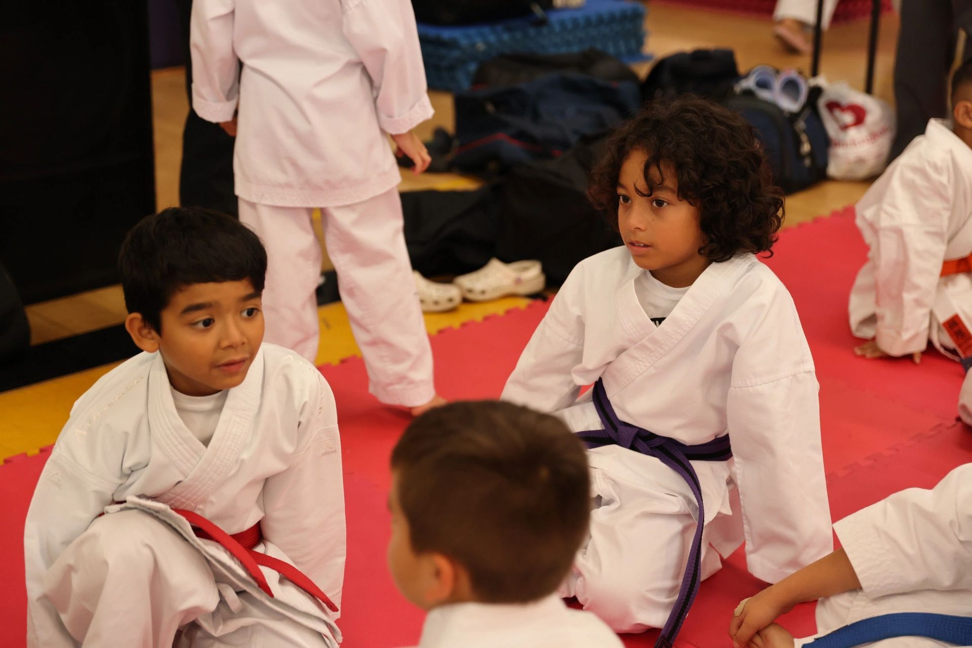 A group of young boys in karate uniforms are sitting on a mat.