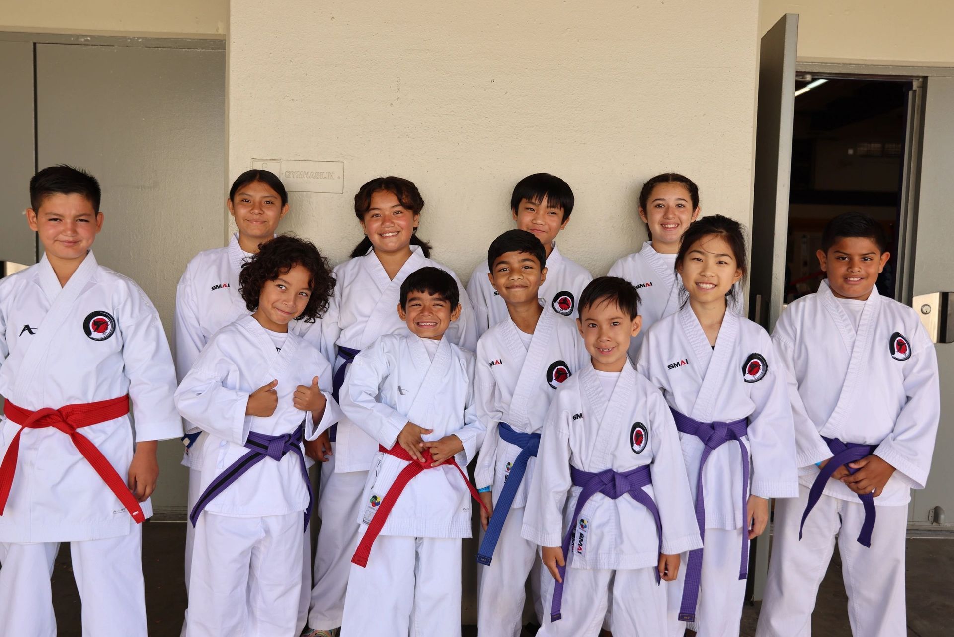 A group of children in karate uniforms are posing for a picture