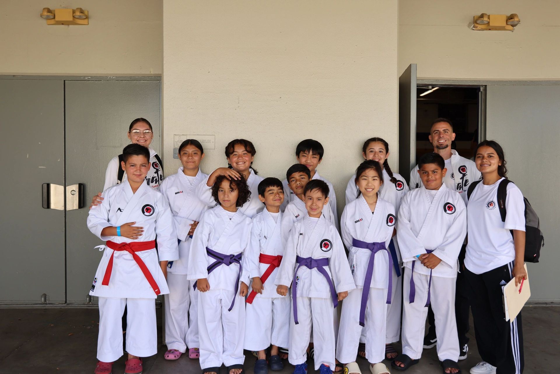 A group of kids in karate uniforms pose for a picture