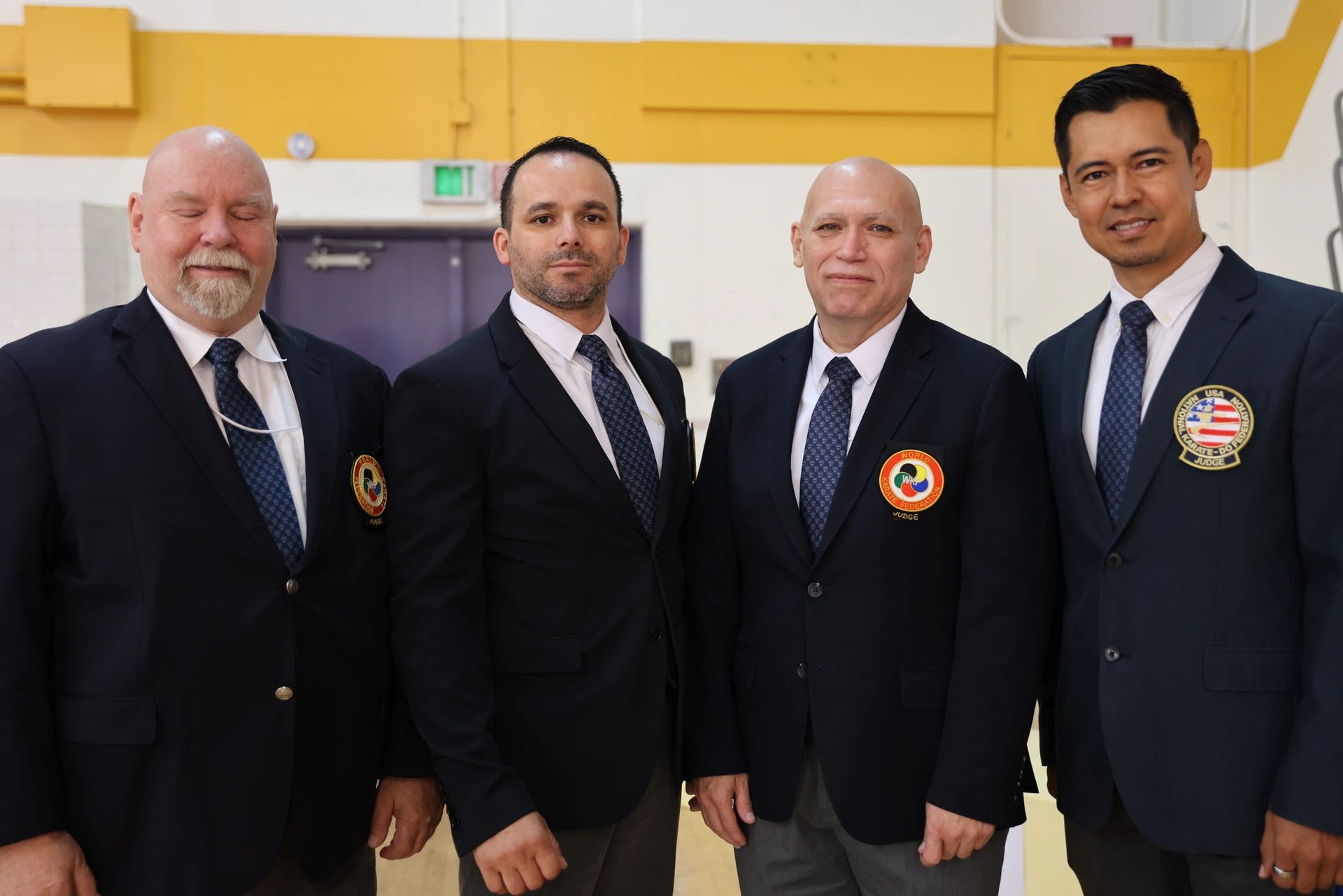 Four men in suits and ties are posing for a picture