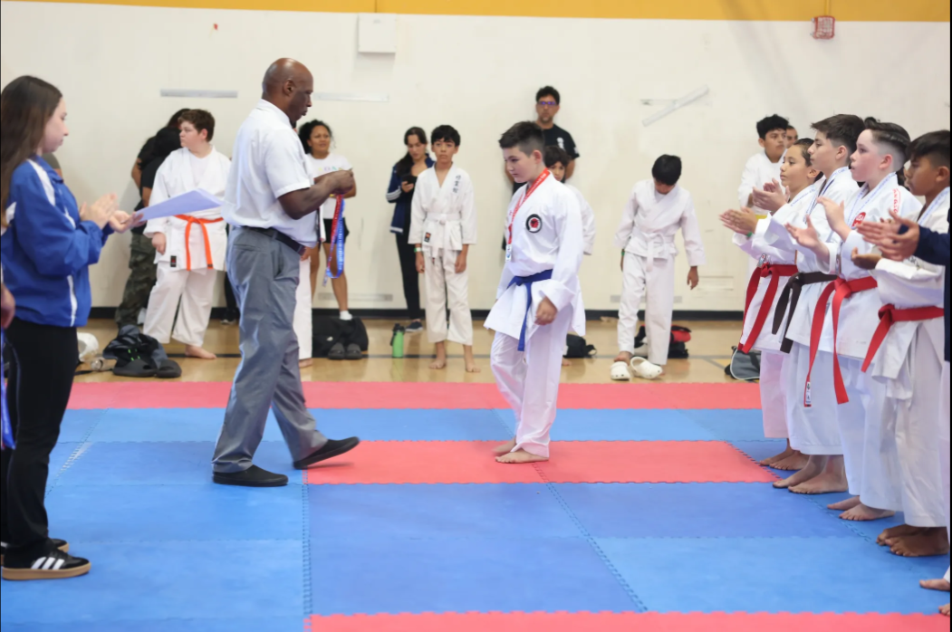 A group of people in karate uniforms are standing on a mat