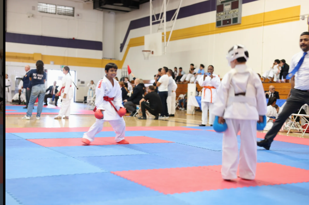 A group of kids are practicing martial arts in a gym.