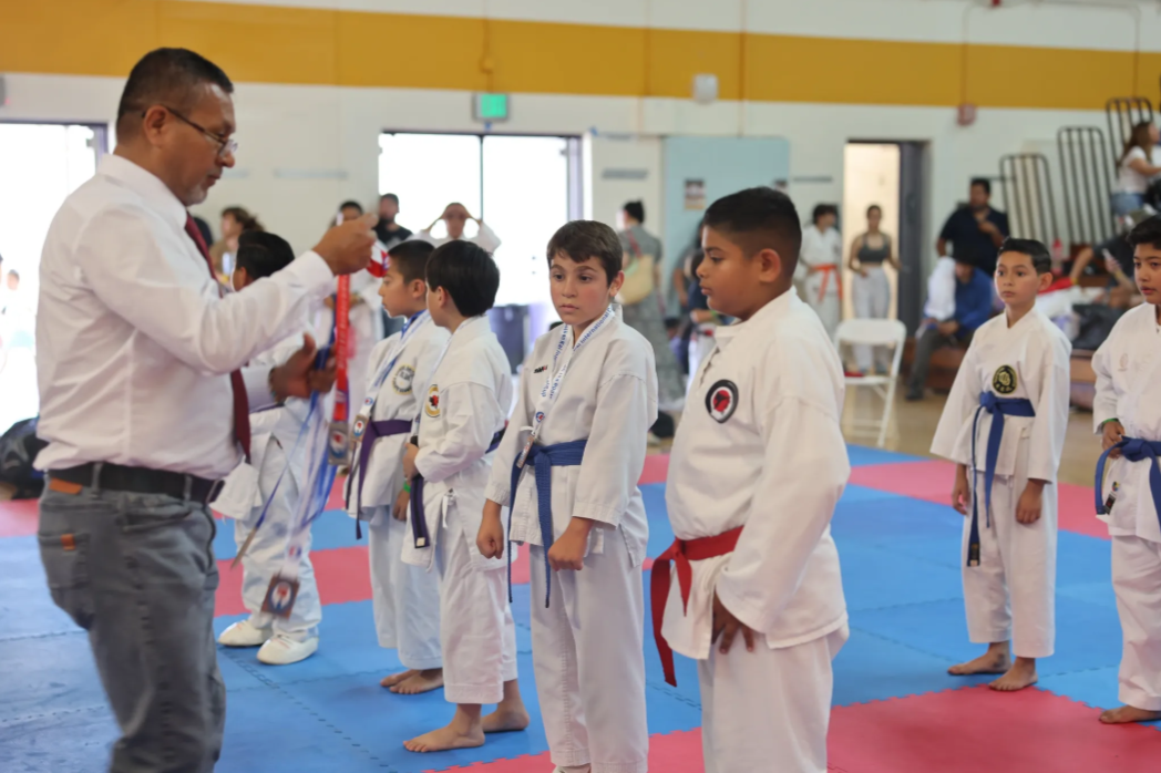 A man is giving a medal to a group of young boys in karate uniforms