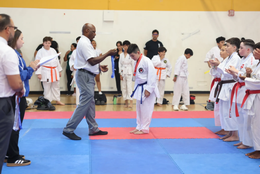 A man is giving a medal to a young boy in a gym.