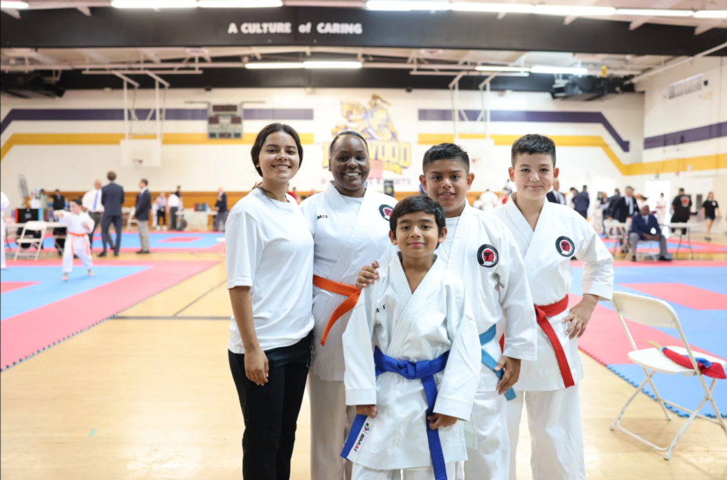 A group of people in karate uniforms are posing for a picture in a gym.