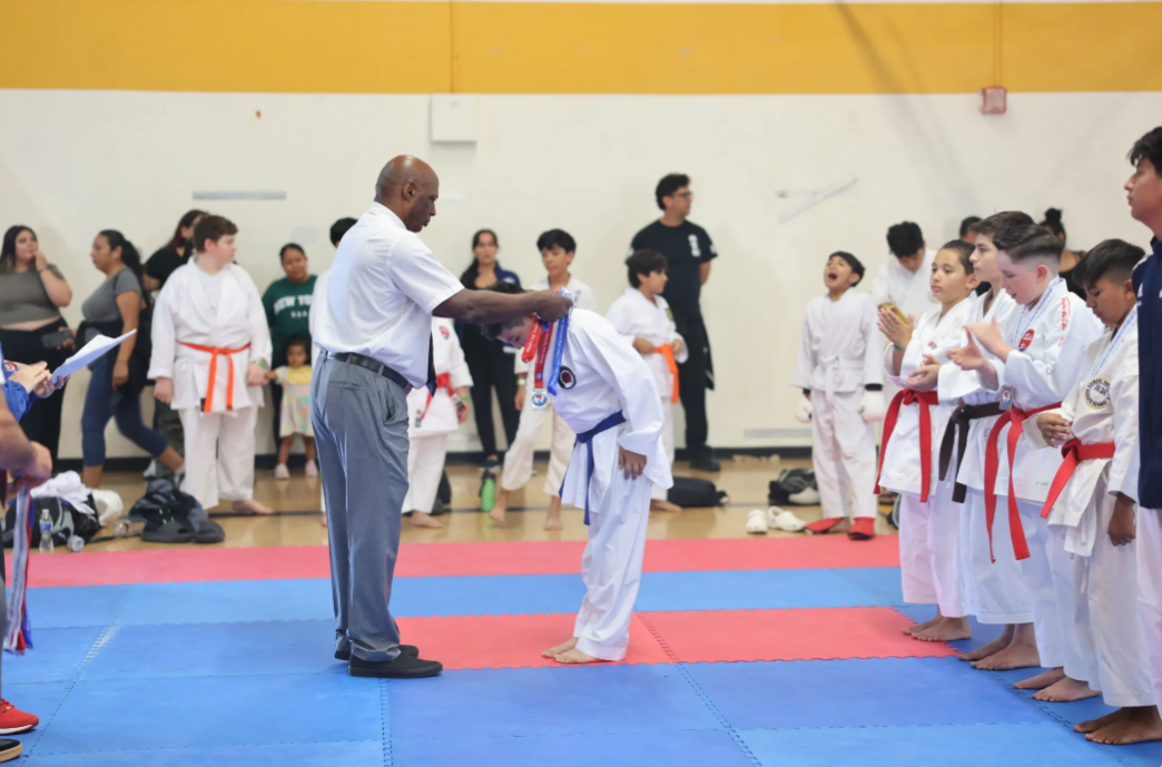 A man is giving a medal to a karate kid