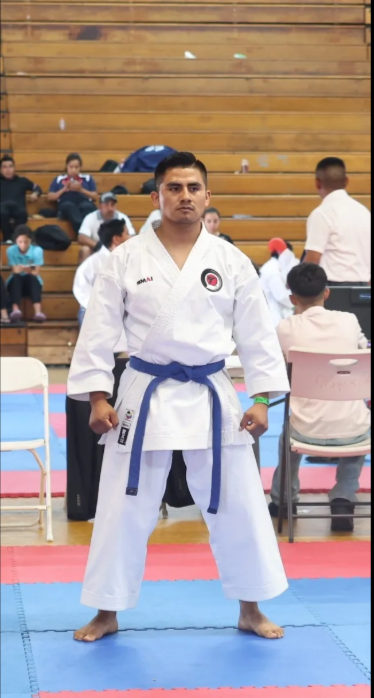A man in a white karate uniform with a blue belt
