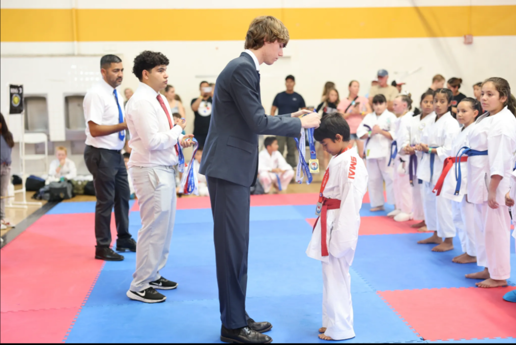 A man in a suit is giving a medal to a young boy.