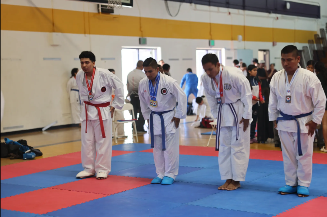 A group of young men in karate uniforms are standing on a mat