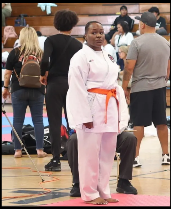 A woman in a white karate uniform with an orange belt