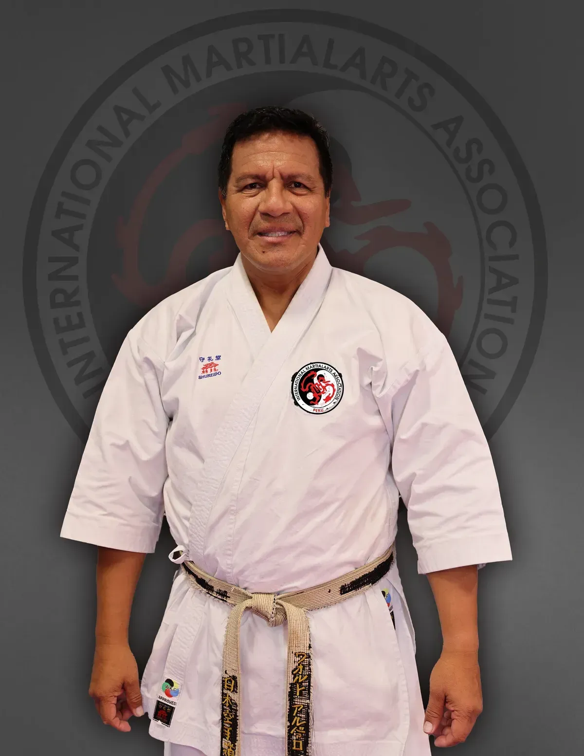 A man in a karate uniform is standing in front of an international martial arts association logo