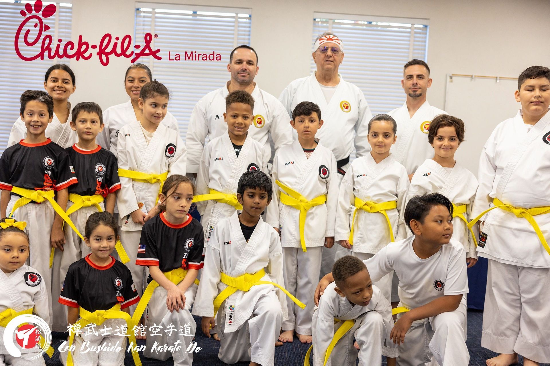 A group of children wearing karate uniforms and yellow belts are posing for a picture.