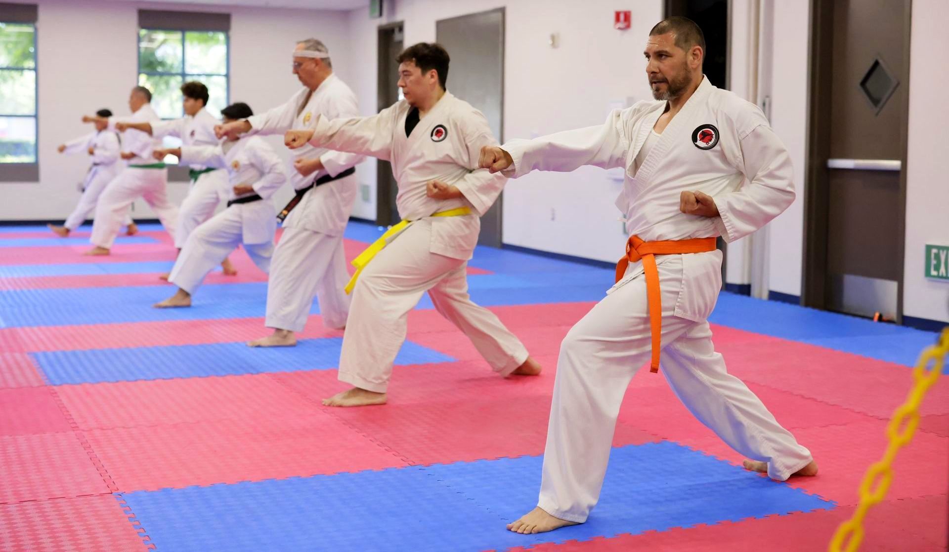 A group of men are practicing karate in a gym.