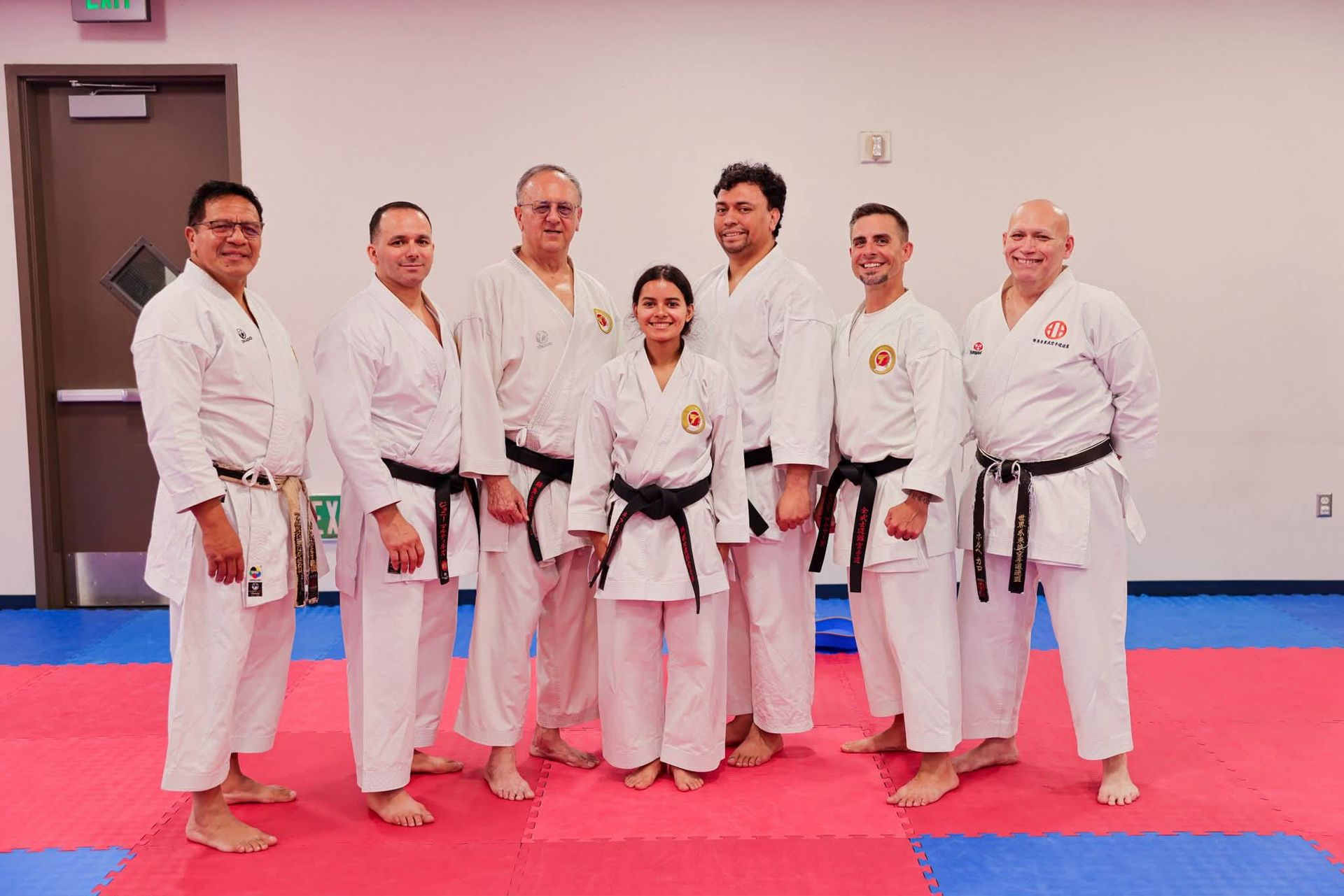 Karate practitioners in white uniforms pose on a training mat.