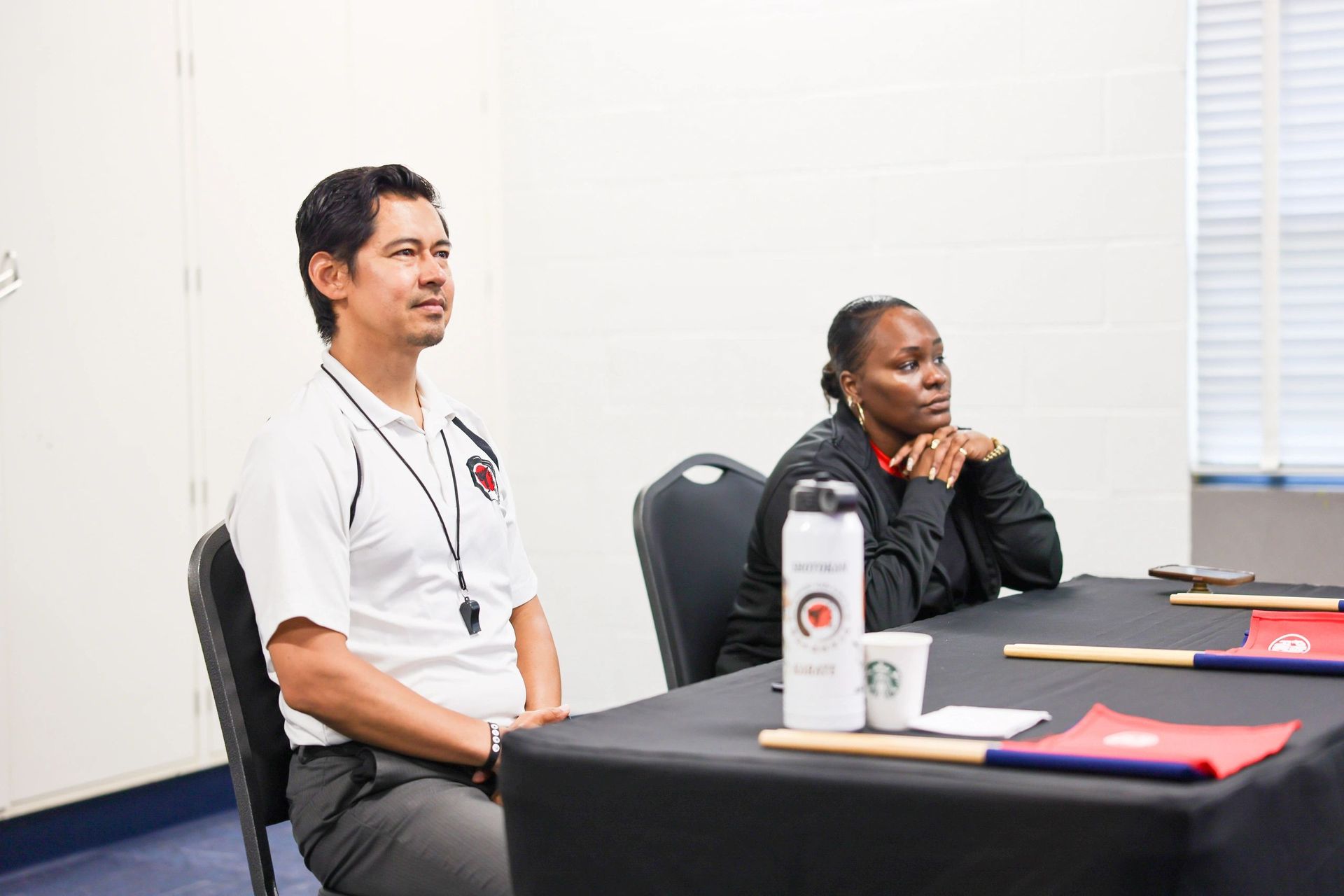 A man and a woman are sitting at a table in a room.