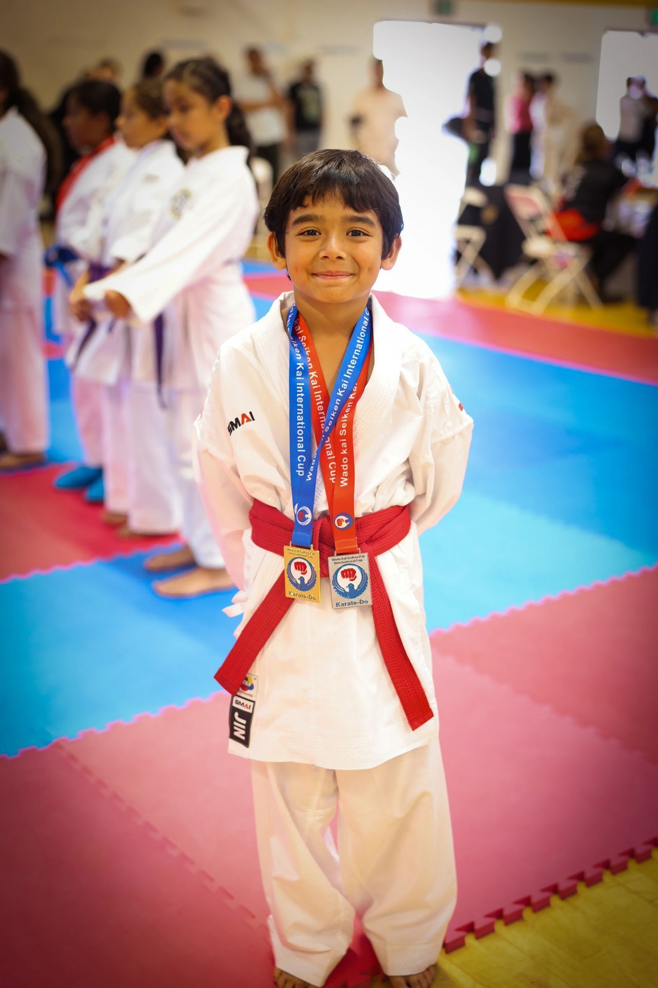 A young boy in a karate uniform is wearing a medal around his neck.