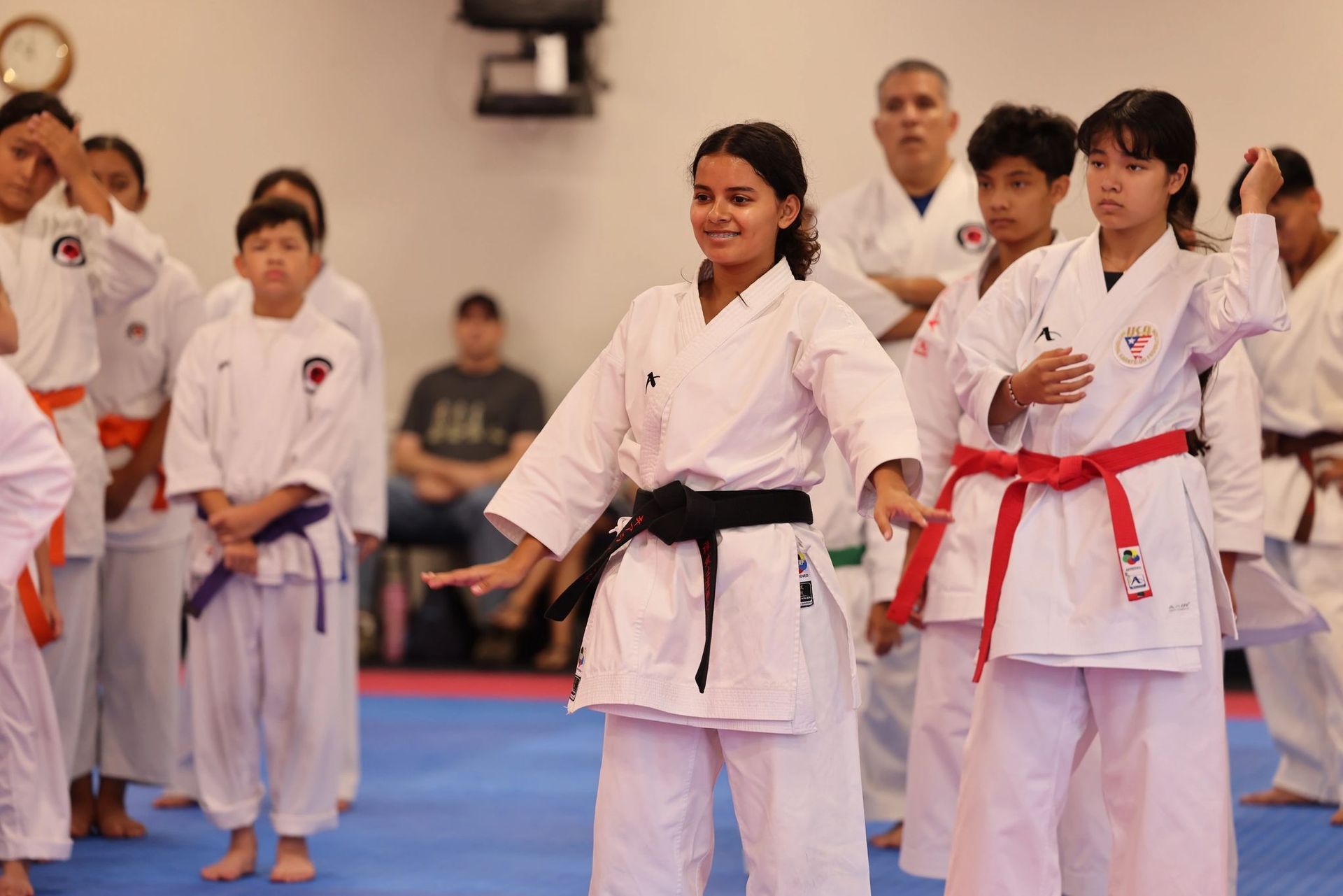 A group of young girls are practicing karate in a gym.