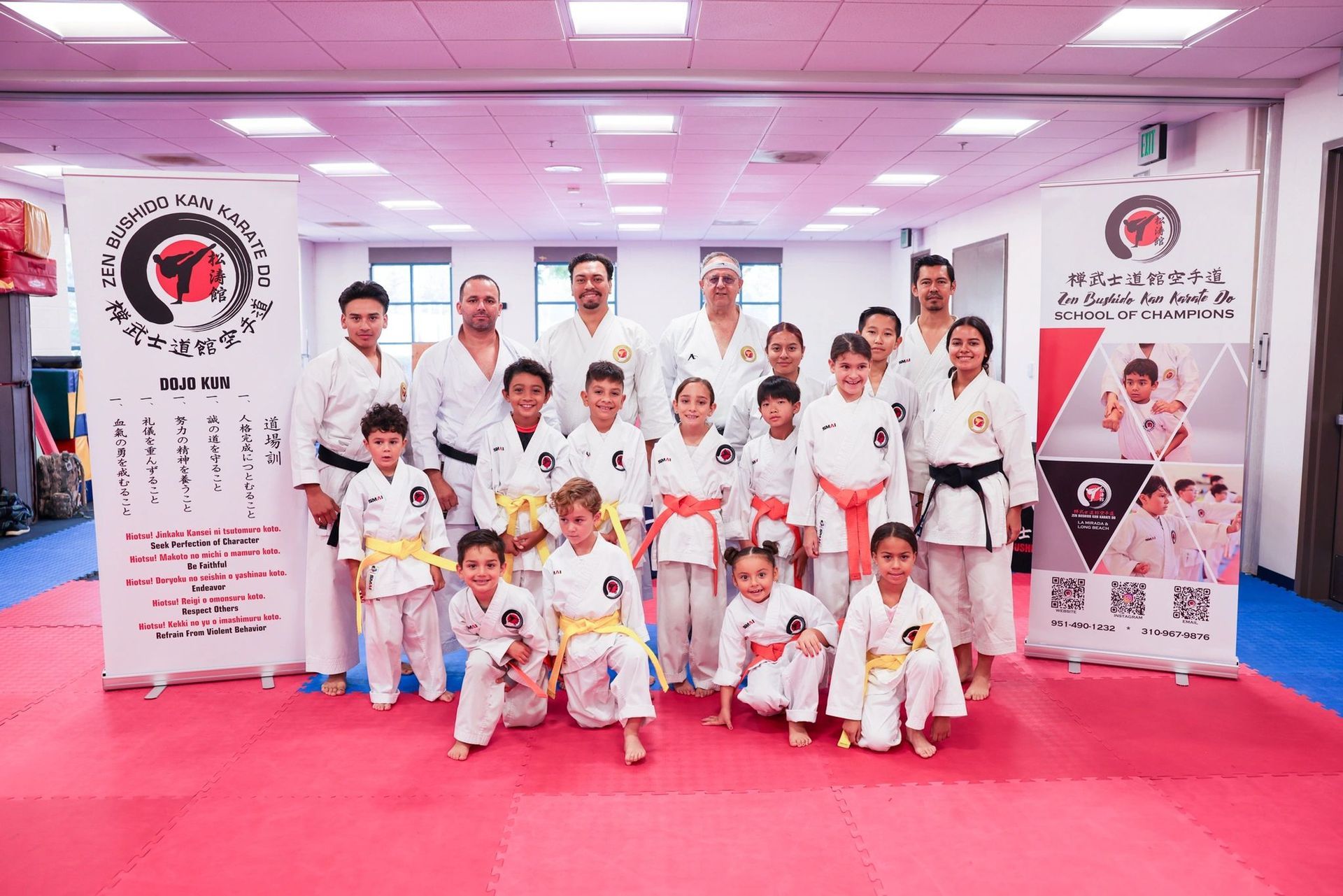 A group of people in karate uniforms are posing for a picture in a gym.