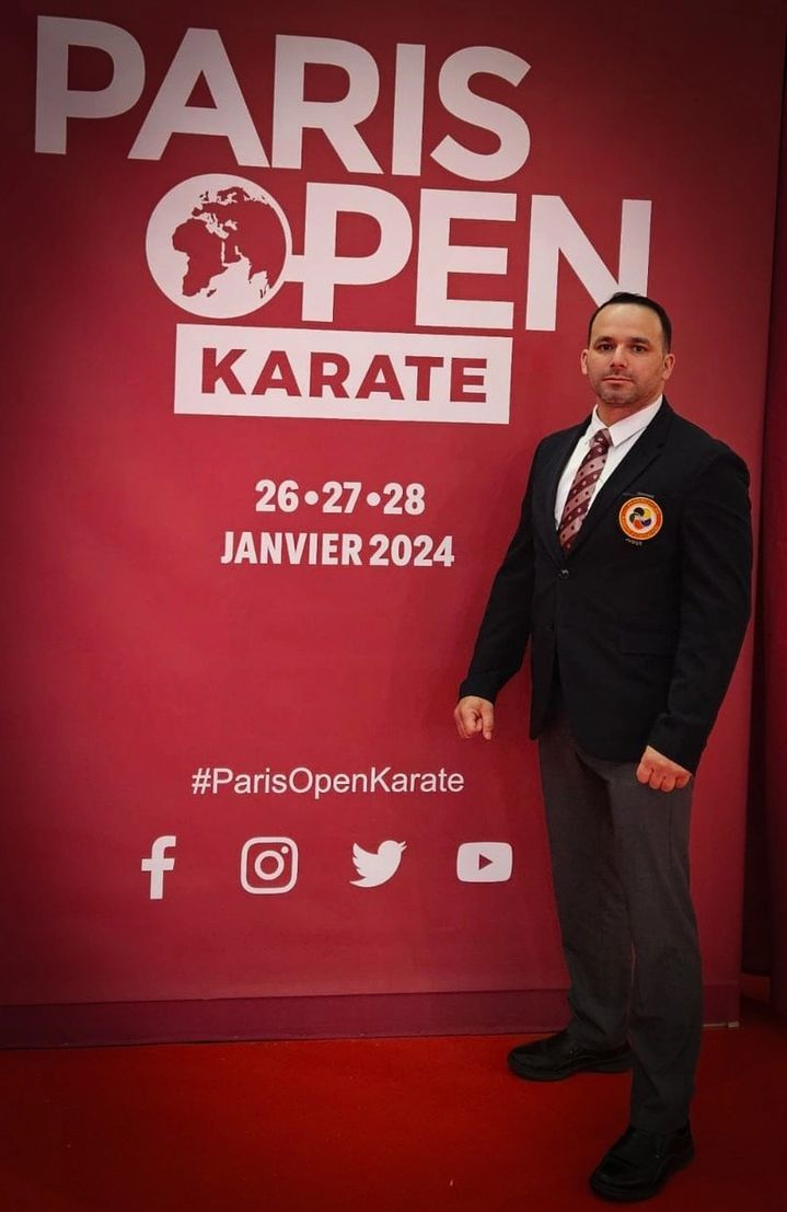 A man standing in front of a paris open karate sign