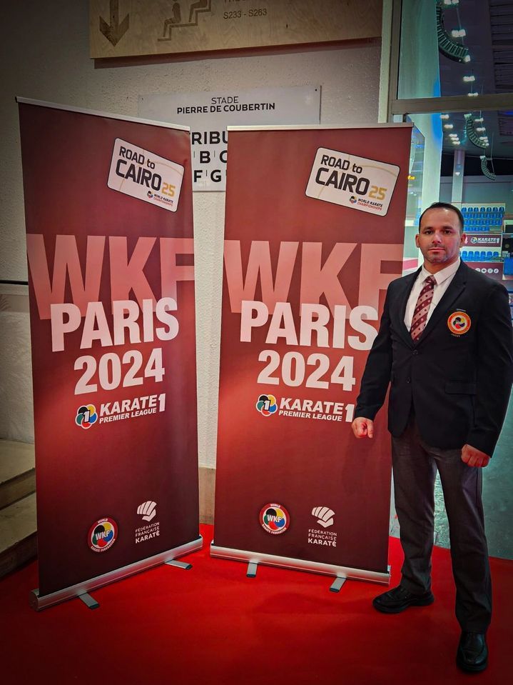 A man in a suit and tie is standing in front of a sign that says wkf paris 2024