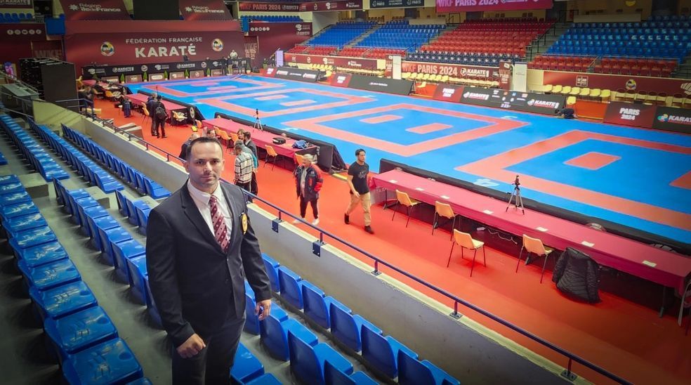 A man in a suit and tie is standing in an empty karate stadium