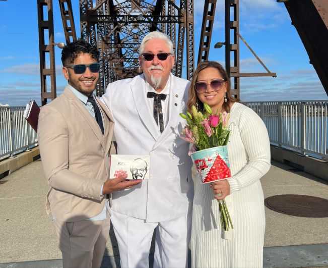 A man dressed as kentucky fried chicken poses with a bride and groom