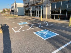A handicapped parking spot is painted on the road in front of a building.