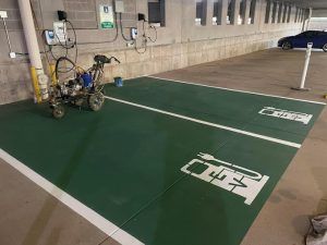 A machine is painting a parking lot in a parking garage.