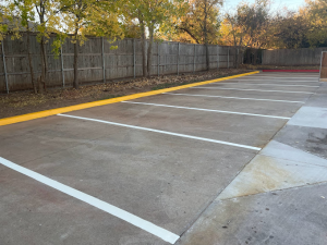 A parking lot with white lines and a yellow curb.