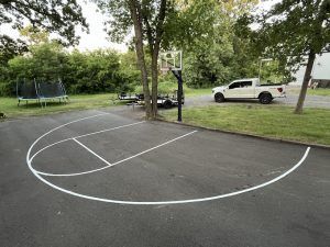 A white truck is parked on the side of a basketball court.