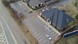 An aerial view of a parking lot with cars parked in front of a building.