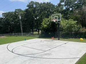 There is a basketball hoop in the middle of a concrete court.