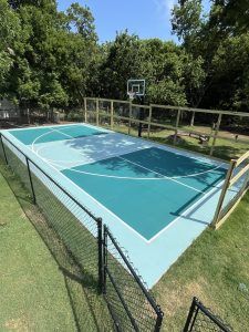 A basketball court surrounded by a chain link fence and trees.