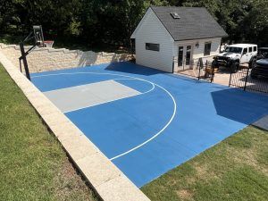 There is a basketball court in the backyard of a house.