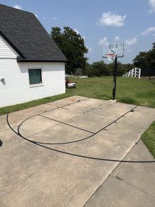 There is a basketball hoop in the backyard of a house.