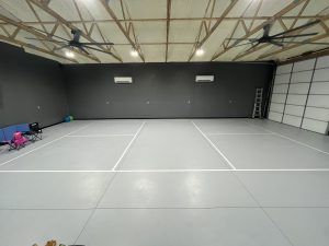 There is a tennis court in the middle of a garage.