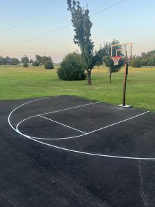 A basketball court with a basketball hoop in the middle of a field.