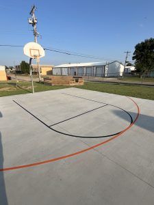 A basketball court in a park with a basketball hoop.
