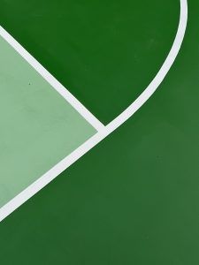 A green basketball court with a white line on it.