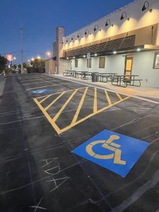 A handicapped parking spot is painted on the asphalt in front of a building.