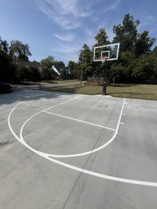 A basketball court with a basketball hoop in the middle of a driveway.