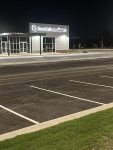 A parking lot in front of a building at night.