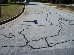 A cracked asphalt road with a cross in the middle