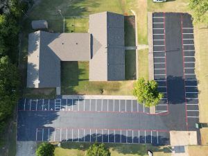 An aerial view of a parking lot with a house in the background.