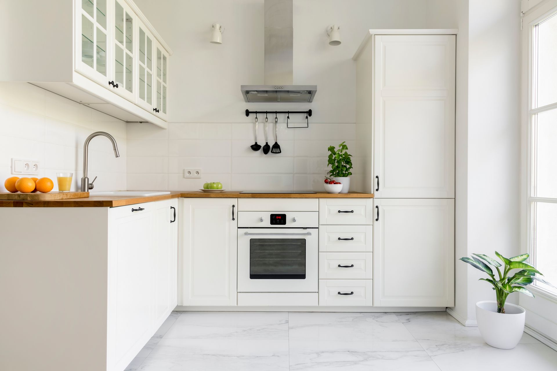 White kitchen with wood countertops, stainless steel appliances, and window.