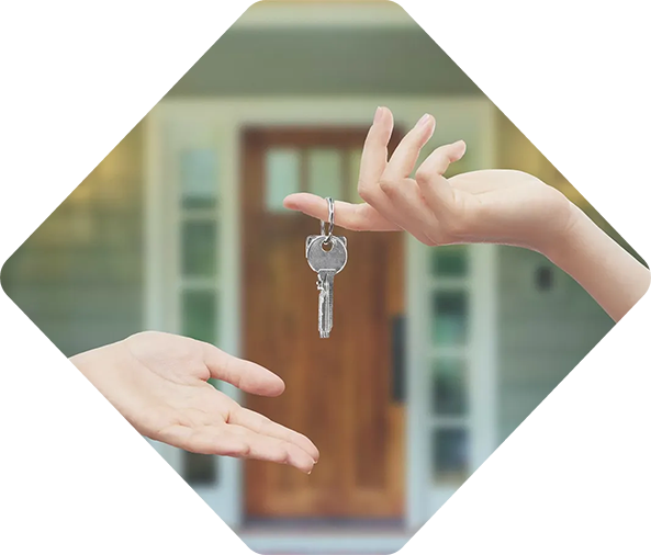 Des mains échangent des clés de maison devant une porte marron floue.