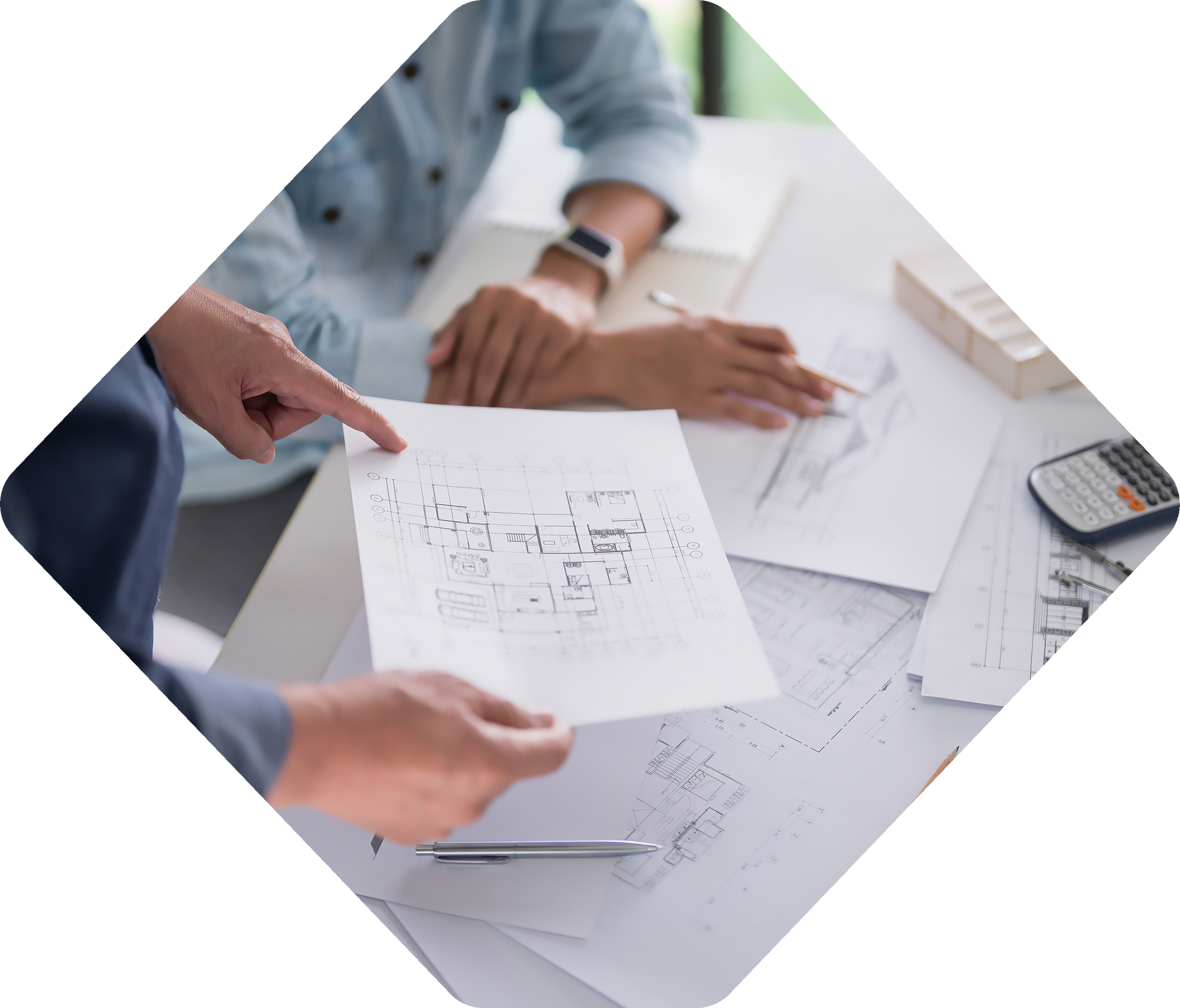 Deux personnes examinant des plans architecturaux, pointant du doigt et discutant des plans.