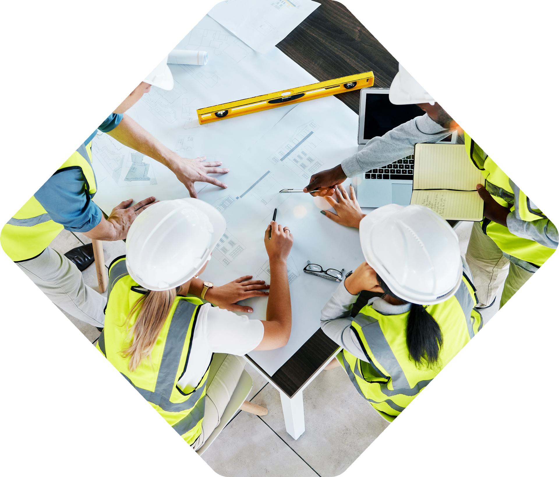 Construction team in hard hats and vests reviewing blueprints at a table.