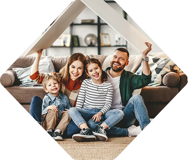 Une famille de quatre personnes souriantes, tenant un toit au-dessus de leurs têtes dans un salon.
